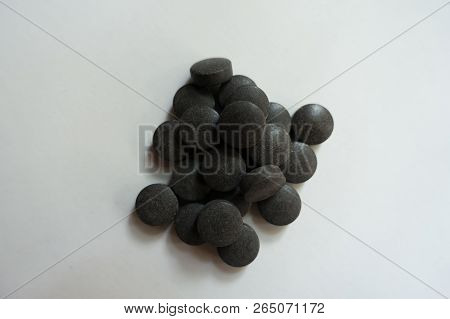 Fistful Of Round Black Pills Of Chelated Iron From Above