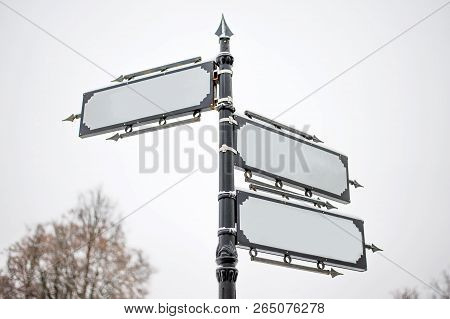 A Metal Pole With Three Vintage Style Signs