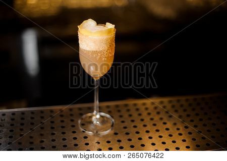 Sweet Wine Glass Filled With Tasty Brandy Crusta Cocktail On The Bar Counter Against Dark Background
