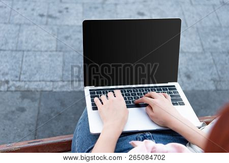 Cropped Image Of Freelancer Using Laptop With Lank Screen On Street