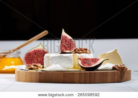 Camembert Cheese On Wrapping Paper With Figs, Nuts And Honey