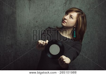 Vintage Portrait Of Beautiful Stylish Girl With Turquoise Earrings And Vinyl Record In Hands On Gray