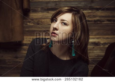 Vintage Portrait Of Beautiful Stylish Girl With Turquoise Earrings In Old Wooden Hut.