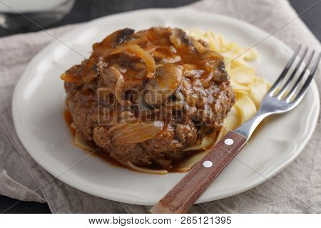 Salisbury steak with pasta under tomato and mushroom gravy