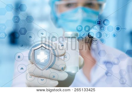 A Female Doctor In The Medical Mask Is Showing A Vaccine In Her Hand In Rubber Glove Behind The Shie