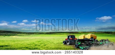 Tractor working in the field. Conducts the processing of crops by chemical means. Beautiful view from above green field of wheat and blue sky in the clouds
