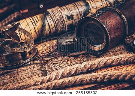 Travel geography navigation concept still life background - old vintage retro compass with sundial, spyglass and rope on ancient world map