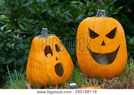 Carved Pumpkins Sitting On Haybail During The Day.