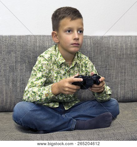 Boy Playing Video Games With Joystic Sitting On Sofa