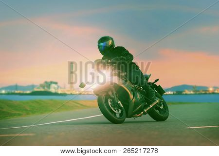 Young Man Riding Sport Touring Motorcycle On Asphalt Highways Against Beautiful Lighting Of Urban In
