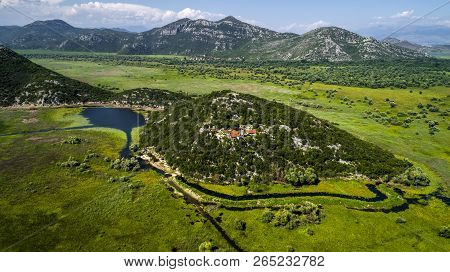 Aerial View Of The Landscape Of Lake Skadar In The Mountain And The Island With Monastery On A Beaut