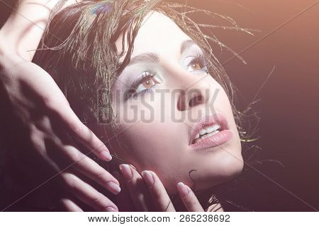 Portrait of a young girl with evening make-up and feather decora