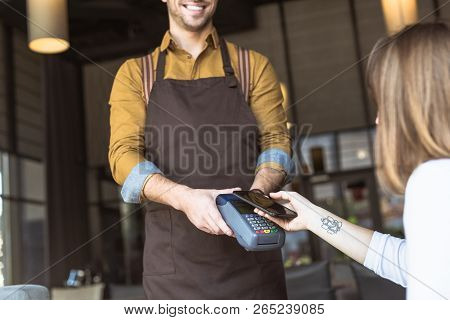 Cropped Shot Of Smiling Waiter Holding Payment Terminal While Customer Doing Contactless Purchase Wi