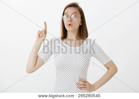 I Got Excellent Idea. Excited Cute Caucasian Girl In Glasses, Holding Hand On Hip And Raising Index 