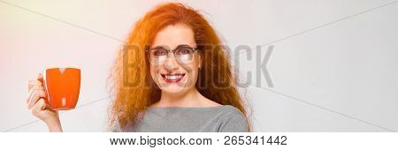 Charming Young Girl With Red Hair. A Young Girl In A Gray Sweater. Young Girl On A Gray Background. 