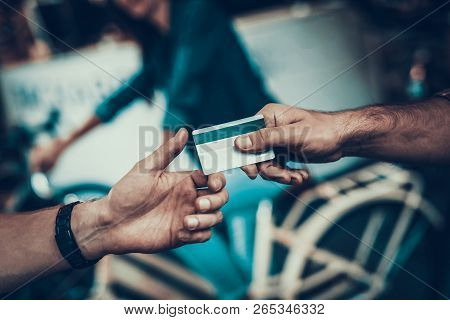 Closeup Of Male Hand Gives Credit Card To Seller. Shop Assistant Hand Takes Card With Blurred Custom