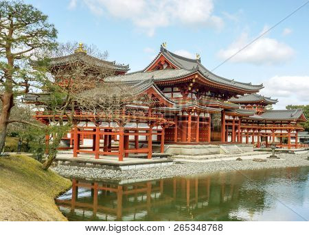 Side View Of Byodoin Japanese Buddhist Temple Under Bright Blue Sky With Clouds. Byodoin Temple Is T