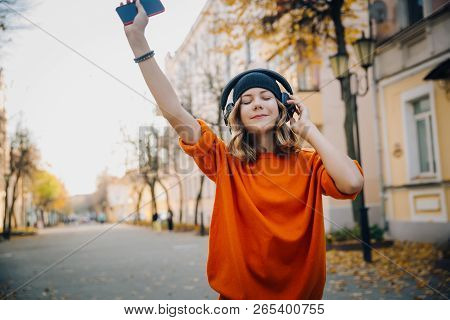 Cute Young Girl Listening Music In Headphones, Dansing And Holding Mobilephone In Hand, Urban Style,