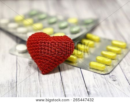 Medical Pills And Red Knitted Heart On Light Wooden Table, Selective Focus. Concept For Health Care,