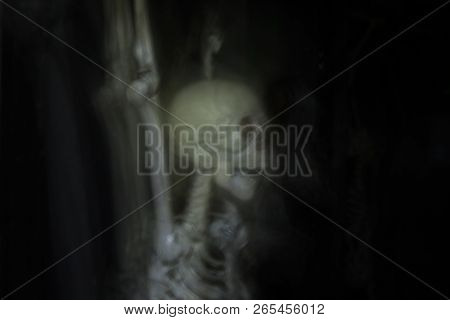 Skeleton Hanging In The Darkness Ready To Scare People. Intentional Motion Blur To Convey Movement A