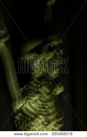 Skeleton Hanging In The Darkness Ready To Scare People. Intentional Motion Blur To Convey Movement A