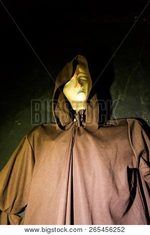 Hooded Figure Looms Creepily By A Black Wall