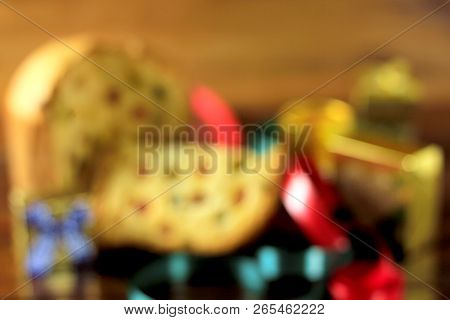 Blurred Christmas Background. Wooden Table With Panetone Decoration And Gift Boxes. Front View