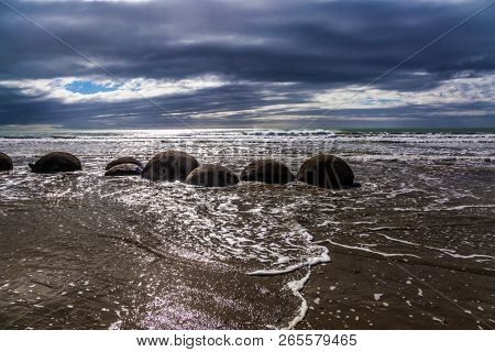Boulders Moeraki - a group of large spherical boulders on the beach Koekokhe. Ocean evening tide. Travel to New Zealand. The concept of active, eco and photo tourism