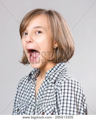 Silly Girl Making Grimace - Funny Face. Child On Gray Background. Emotional Portrait Of Caucasian Te