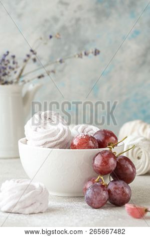 Colorful Zephyr And Grape On White Wooden Background.set Of Homemade White And Pink Zephyr Or Marshm