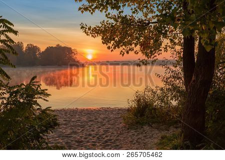 Sunrise Over The Plain River With Sandy Bank And Trees On A Foreground, Forest On The Opposite Bank 
