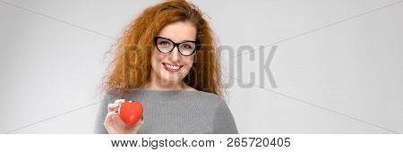 Charming Young Girl With Red Hair. A Young Girl In A Gray Sweater. Young Girl On A Gray Background. 