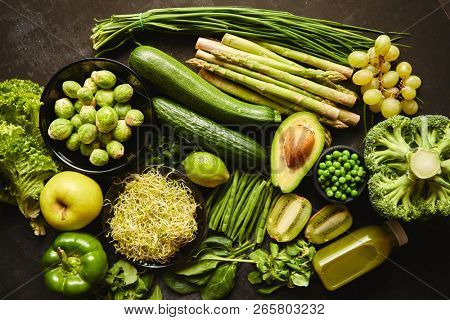 Green healthy food composition with avocado, broccoli, apple smoothie cucomber asparagus kiwi bean. Placed on dark background. Top view.