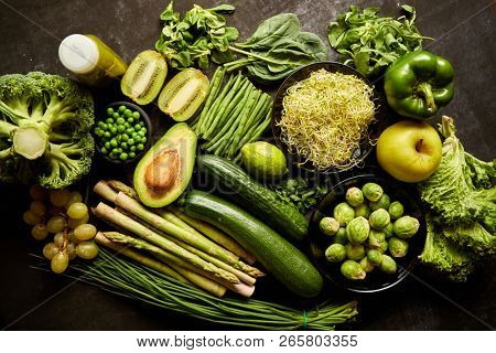 Green healthy food composition with avocado, broccoli, apple smoothie cucomber asparagus kiwi bean. Placed on dark background. Top view.