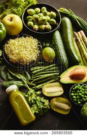 Green healthy food composition with avocado, broccoli, apple smoothie cucomber asparagus kiwi bean. Placed on dark background. Top view.