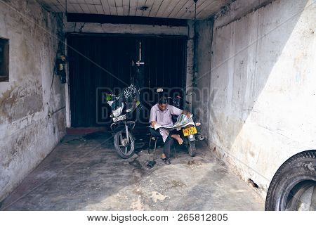 Matara, Sri Lanka - January 8, 2017: A Man Reads A Newspaper Near Their Motorcycles In The Shade