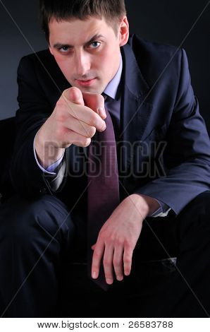 Mladý muž v obleku ukazuje na vás, focusrd na straně