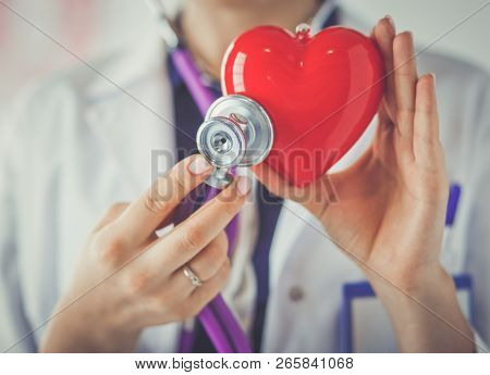 A doctor with stethoscope examining red heart, isolated on white background