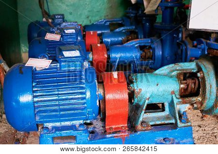 Old, Rusty Scratches Water Pump With An Electric Motor Dyed In Blue Color On The Cold Water Pipe.