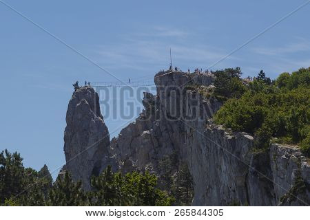 The Passage Of Tourists On A Suspension Rope Bridge Between The Mountains.