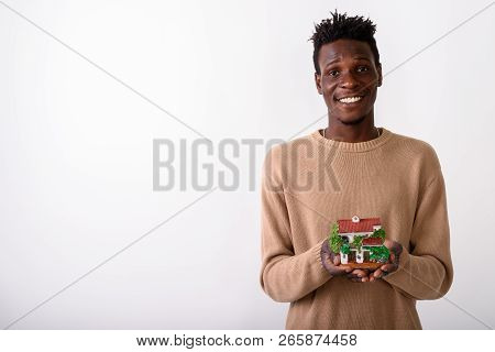 Studio Shot Of Young Happy Black African Man Smiling While Holdi
