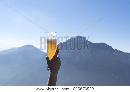 Hands Lifting Draft Beer Glass And Happy Enjoying Harvest Time At Outdoor On Beautiful Mountain Scen