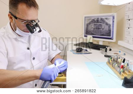 MOSCOW - JAN 10, 2018: Chief of clinic with portable microscope works with denture with special tools in Razumenko clinic