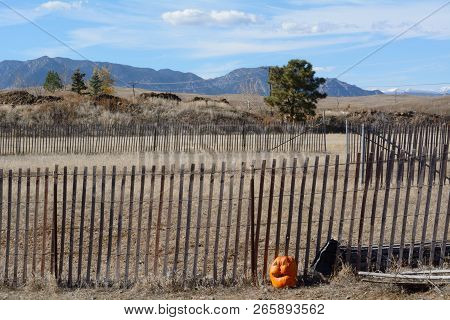 Rural Halloween Colorado Landscape With Jack O Lantern Carved Pumpkin Next To Fence And Rocky Mounta