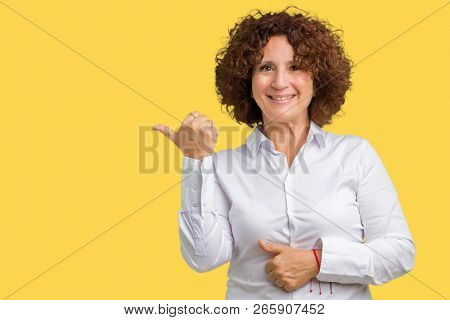 Beautiful middle ager senior businees woman over isolated background smiling with happy face looking and pointing to the side with thumb up.