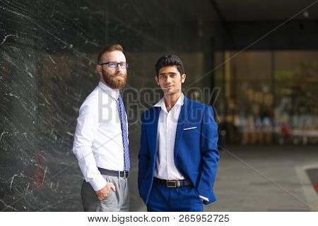 Serious Young Multi-ethnic Men Standing Near Office Building And Looking At Camera. Confident Handso