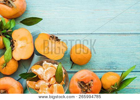 Healthy Diet Concept. Fresh Ripe Persimmons And Tangerines On Blue Wooden Background Top View Flt La