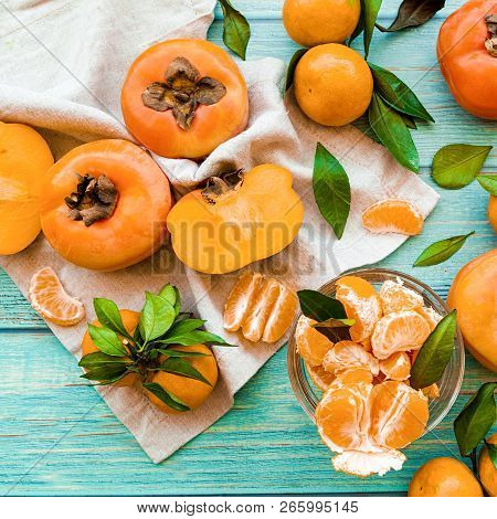 Healthy Diet Concept. Fresh Ripe Persimmons And Tangerines On Blue Wooden Background Top View Flt La