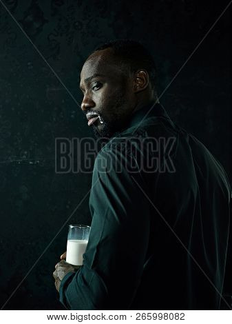 Healthy Young African Man Holging Cup Of Milk On A Bllack Studio Background.
