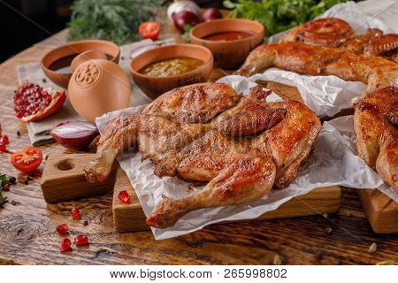 Chicken Tabaka On A Wooden Background With Sauces Of Different Types. Rich Laid Table.